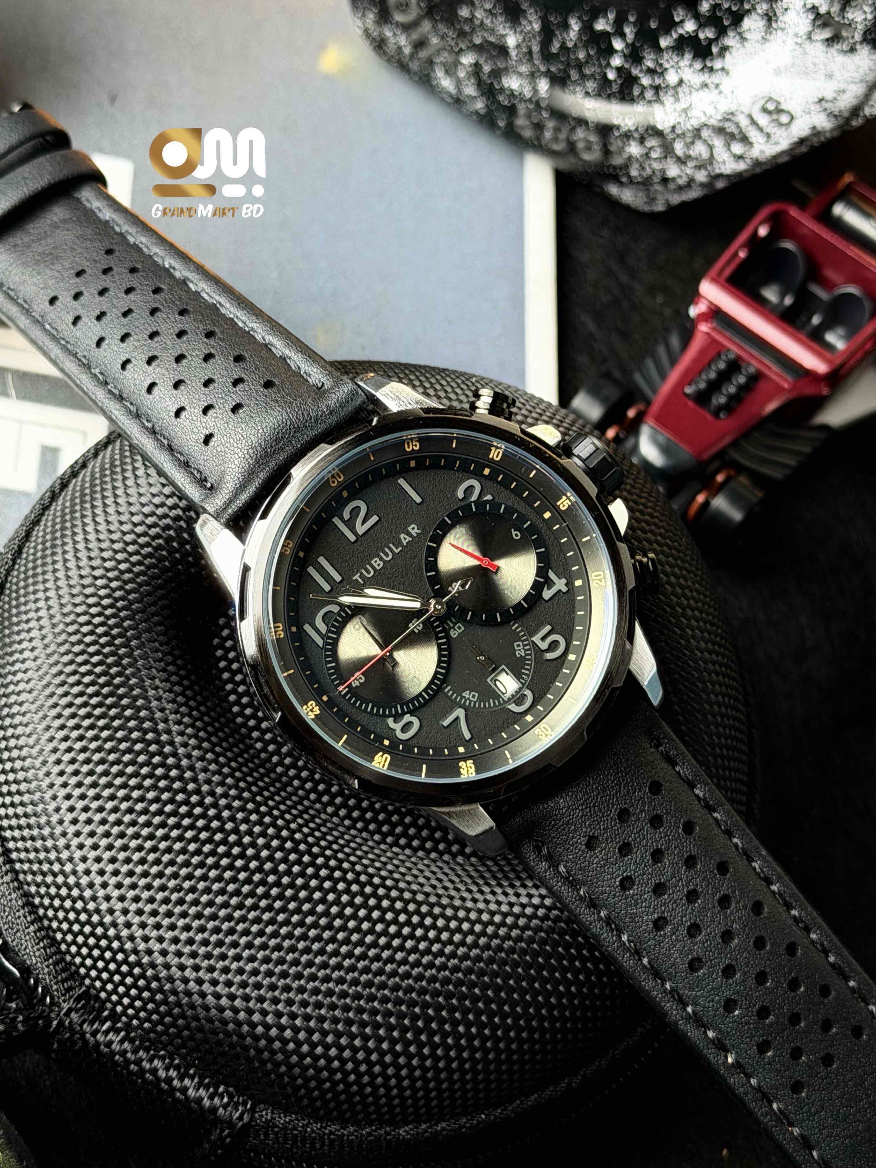 Tubular featuring a black chronograph-style textured dial with numeric markers and a perforated black leather strap.