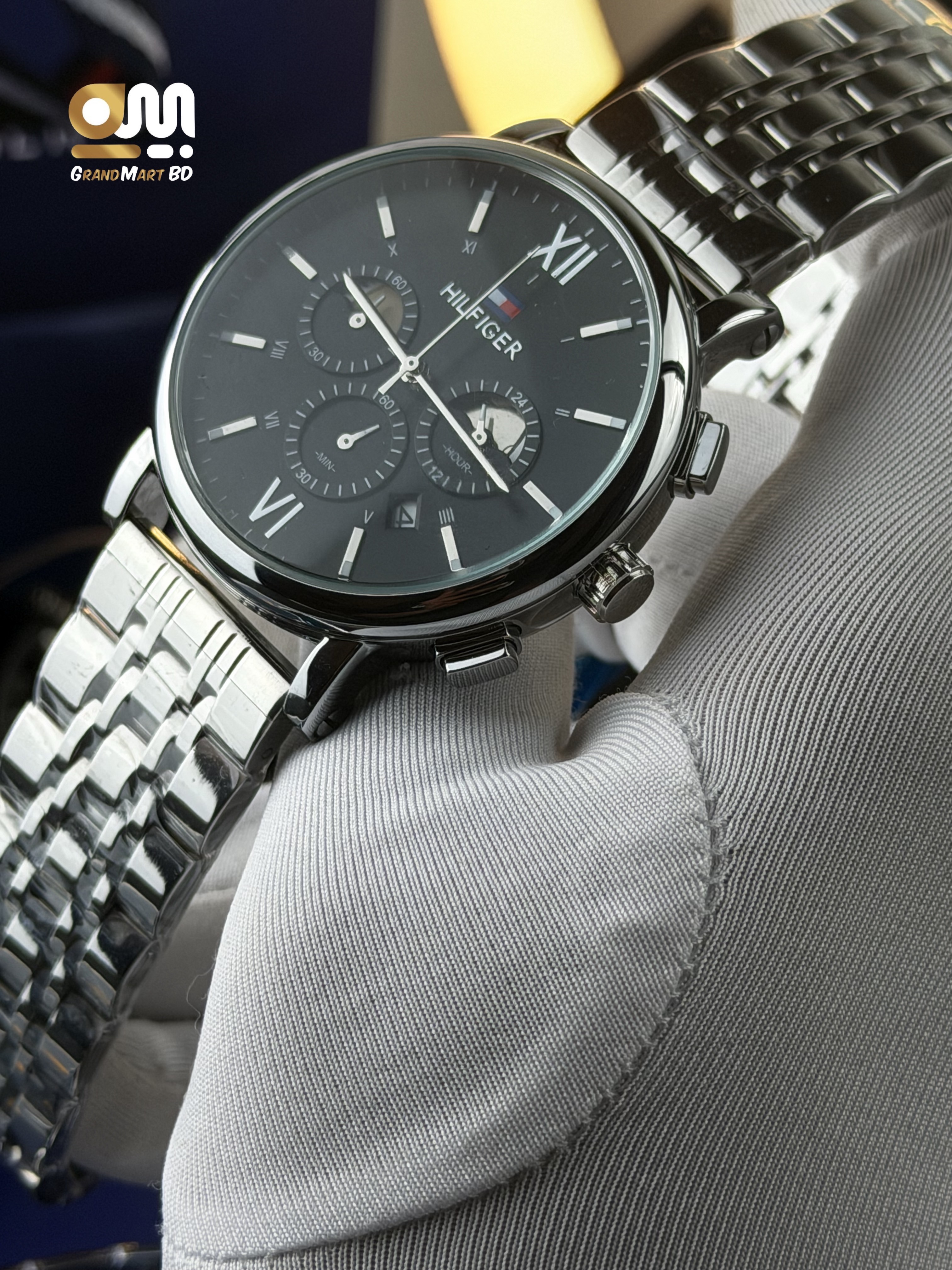 Tommy Hilfiger quartz men's watch featuring a black dial, Roman numeral markers, multi-function/chronograph sub-dials, and a stainless steel link bracelet