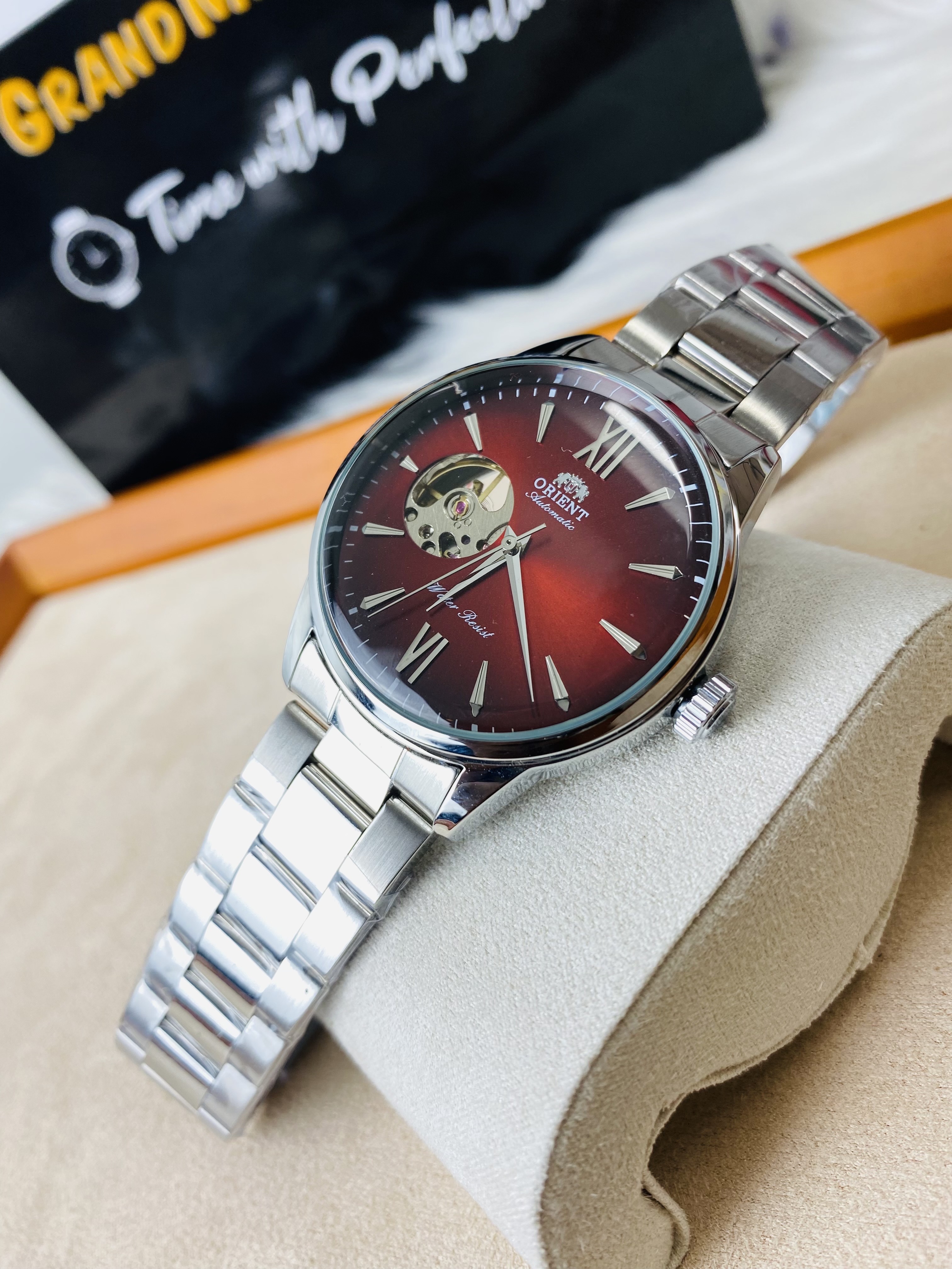 Orient Bambino Open Heart automatic men's watch with a red dial and a stainless steel bracelet.